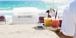 Waiter brings cocktail to resort guests on the beach.